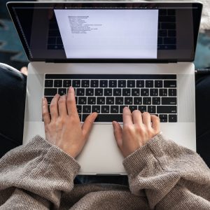 Photo of a woman's hand working on a laptop, top view