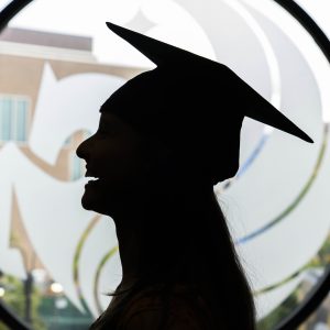 sillouette of graduate in front of UCF Pegasus in the window